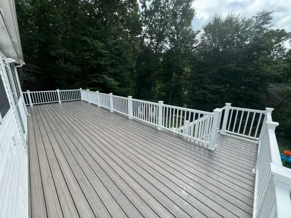 Large elevated backyard deck with gray boards and white railings in Bellingham, MA